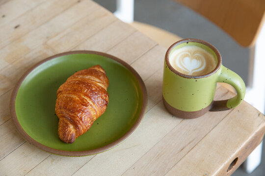 latte and croissant with green dishes
