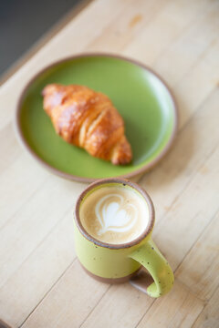 latte and croissant with green dishes