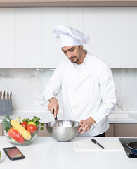 Young handsome male chef posing while cooking in the kitchen