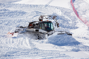 Fototapeta na wymiar A snowplow in action shoveling snow in the mountains. A man at work driving a snow blower in the mountains. Working in mountains with snow
