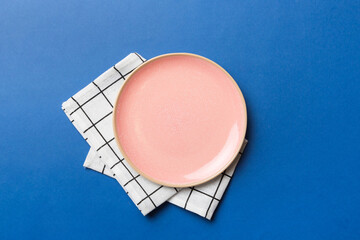 Top view on colored background empty round pink plate on tablecloth for food. Empty dish on napkin with space for your design