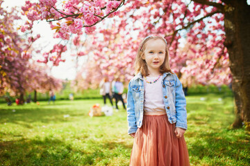 preschooler girl in tutu skirt enjoying nice spring day in cherry blossom garden