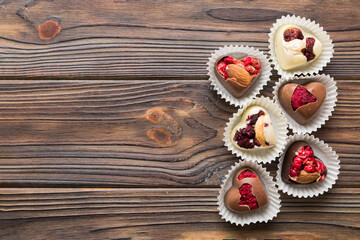 Fototapeta na wymiar chocolate sweets in the form of a heart with fruits and nuts on a colored background. top view with space for text, holiday concept