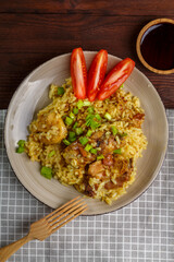 Fried chicken pieces in soy and pad thai sauce in a plate on a blue napkin on a table with spices.