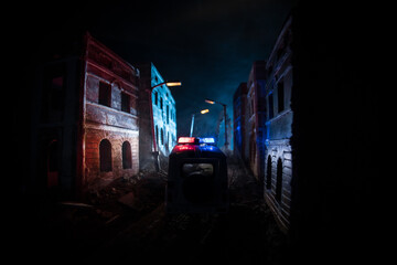 Naklejka na ściany i meble Police raid at night and you are under arrest concept. Silhouette of handcuffs with police car on backside. Image with the flashing red and blue police lights at foggy background. Slider shot