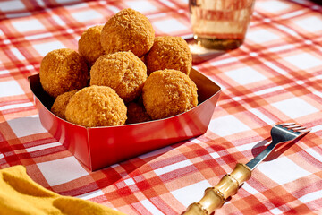 Typical Sicilian street food arancini (deep fried rice balls with meat) on paper plate take out. Unhealthy food.