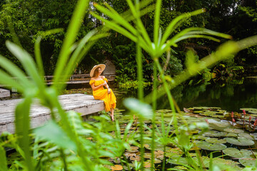 Young woman on wooden bridge on lake, enjoy tropical garden in resort