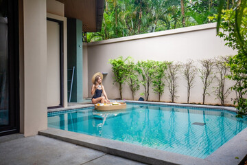 Obraz na płótnie Canvas Female traveler enjoying a delicious floating breakfast in a modern tropical villa