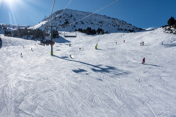 Ski slope with skiers sliding down the slope in the Pyrenees, Andorra, photo with copyspace. - obrazy, fototapety, plakaty