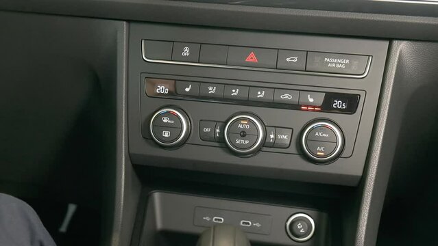 Panel de aire acondicionado de un automovil con botones de asiento y alerta de pare del vehiculo, radio 