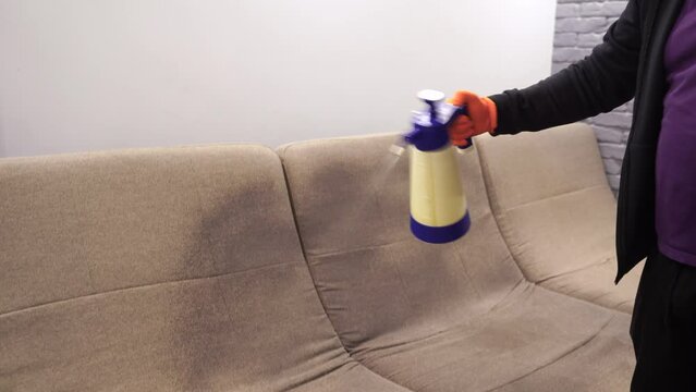 4k video spraying detergent on couch for dry cleaning using extractor machine. Process of dry cleaning for removing stains and dirt from couch at home. Professional cleaning service.