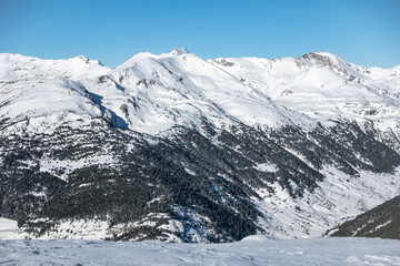 Snowy landscape with trees and high mountains in the mountain range of the Pyrenees, Andorra.