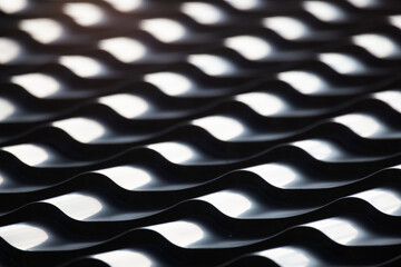 Shiny black roof tiling with wavy shape pattern, close up