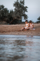 Two European girls enjoy the sunset on the sea, play, hug, smile. Love sisters on the beach. as a gift from daughters mother's day. Family vacation at the hotel. Happy childhood in summer. High