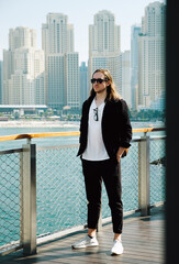 Fototapeta premium Confident young man tourist against skyline of Dubai