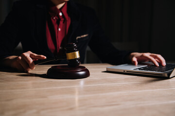 Justice and law concept.Male judge in a courtroom with the gavel, working with, computer and docking keyboard, eyeglasses, on table in morning light