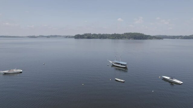 Drone sobrevoando represa onde pode ser visto barcos ancorados em um dia ensolarado