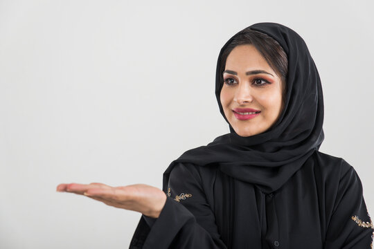 Beautiful woman from Dubai posing on colored background with traditional abaya.