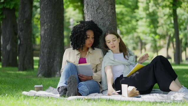 Female students preparing for exams outdoors, discussing books and literature