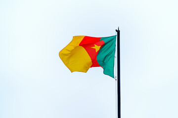 The flag of the Republic of Cameroon flutters in the wind against the sky