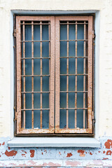 Fototapeta na wymiar Old window with a metal grille of two sections