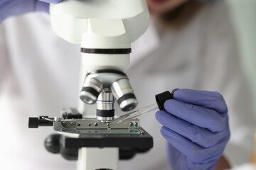 Scientist working with pipette and microscope in laboratory.