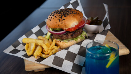 Fotografía close up de hamburguesa con papas y bebida.