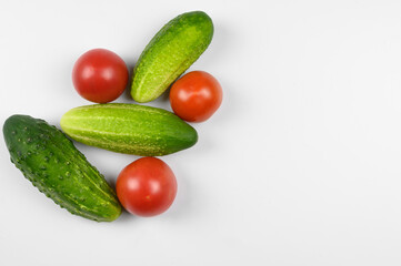 Layout of ripe tomatoes and cucumbers on a white background. The concept of cooking, organic vegetables.