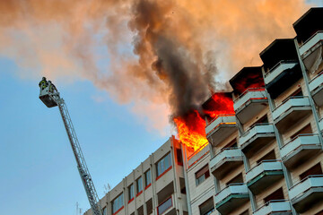 Italian firefighters at work during a fire in an attic of a building in an Italian city. Apartment on fire and flames. 