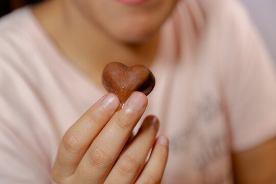 Mujer comiendo chocolate en forma de corazón en primer plano.