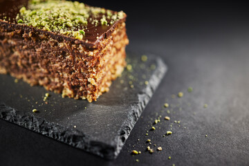 Chocolate cake with walnuts and pistachio isolated on black background. Pastry from homemade bakery