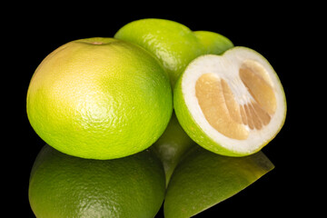 One whole and two half ripe organic Citrus Sweetie, close-up, isolated on black background.