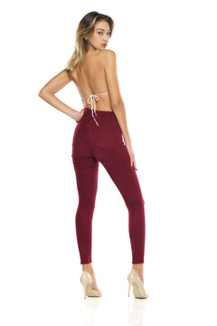a young woman in burgundy jeans and top, and high heels shoes posing on a white background. Rear, back view