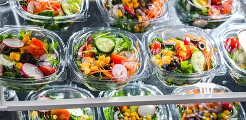 Boxes with pre-packaged vegetable salads in a commercial fridge