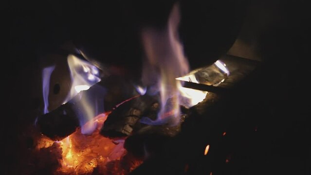 A cauldron stands on a grill with a red-hot fire