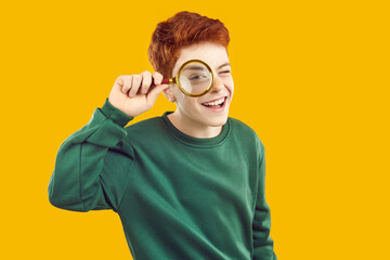 Children's interest. Portrait of cheerful active preteen boy who looks at camera through magnifying...