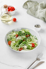 Cucumber salad. Healthy green fresh salad with sliced cucumber, tomatoes, mozzarella cheese on white plate. Diet dinner concept.