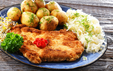 Pork cutlet coated with breadcrumbs with potatoes and cabbage