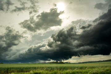 Dark, menacing thundercloud over a green field in summer