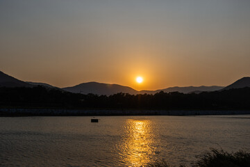 Sunset Behind the Mountains Next to a River