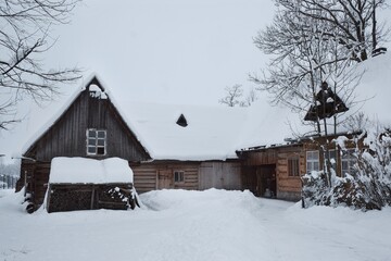 Rural scenery of old wooden cottage covered with snow 
in  village in Podhale, Poland