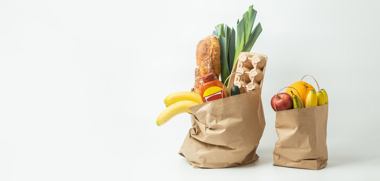 Food products from the grocery shop. Food shopping and delivery concept. Bread, eggs, bananas, fruits and vegetables in the brown paper shopping bag. Healthy nutrition concept
