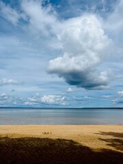 Wild sandy beach and very calm sea horizon, fluffy clouds in the bright sky