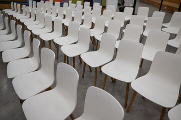 Empty white plastic chairs in a conference room. 