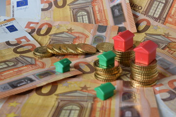 euro banknotes, coins and green and red houses