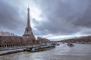 A view across the Seine of the Eiffel Tower under dramatic clouds. 