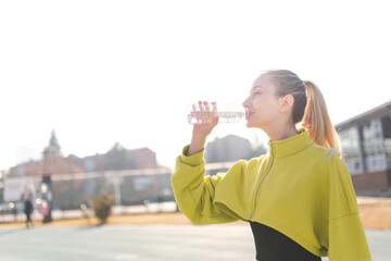 Fototapeta na wymiar Beautiful woman drinking tap water during workout
