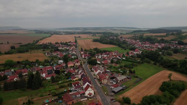 Aer ial view of a German village surrounded by meadows, farmland and forest in Germany.