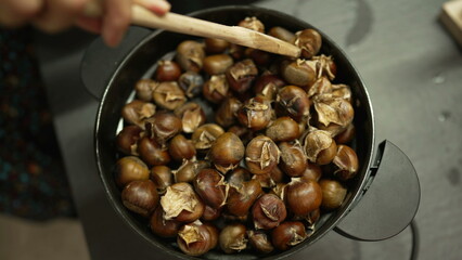 Cooking marrons nuts inside pan stirring with wooden spoon