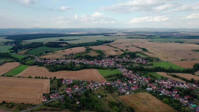 Aer ial view of a German village surrounded by meadows, farmland and forest in Germany.